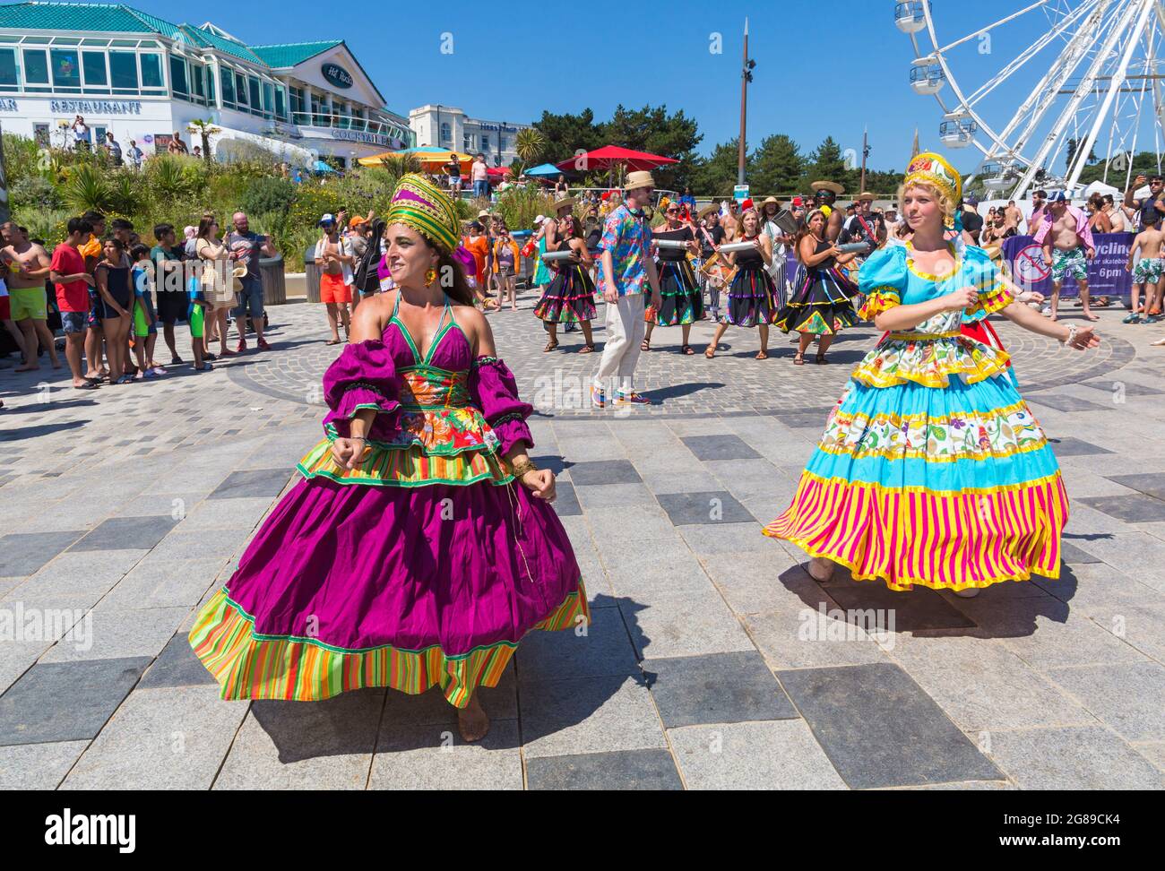 Bournemouth, Dorset, UK. 18th July, 2021. Afon Sistema with their whirling dancers with colourful skirts play Maracatu, Samba's earthier cousin from Northeastern Brazilas perform as part of the Arts by the Sea Summer Series on a hot sunny crowded day at the seaside. Credit: Carolyn Jenkins/Alamy Live News Stock Photo