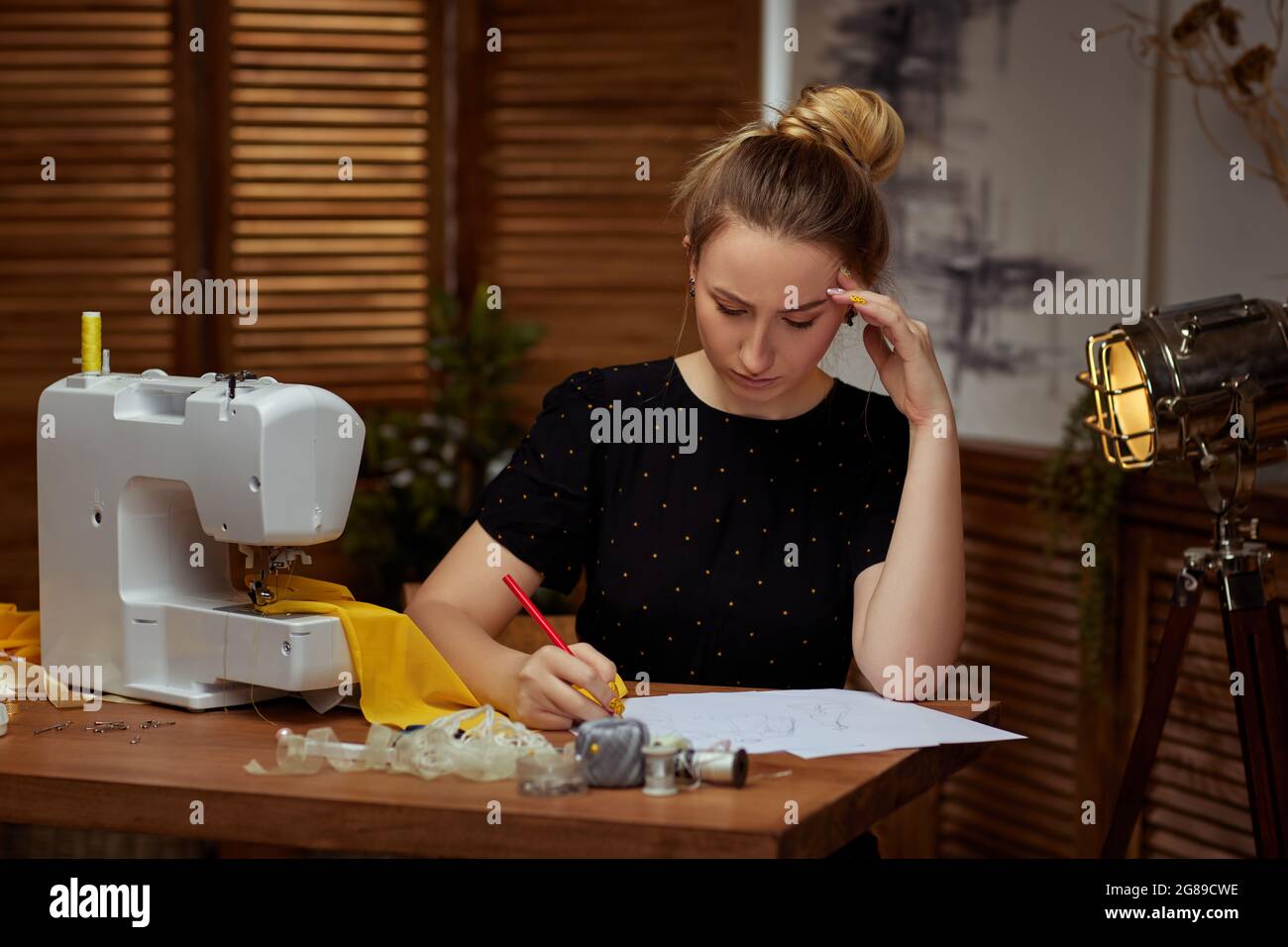 Beautiful young seamstress working on sewing machine Stock Photo