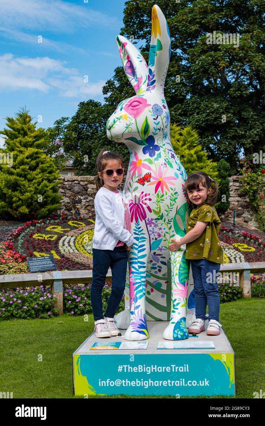 Two young girls with floral giant hare artwork sculpture, The Big Hare Trail event, Lodge Grounds park, North Berwick, East Lothian, Scotland, UK Stock Photo