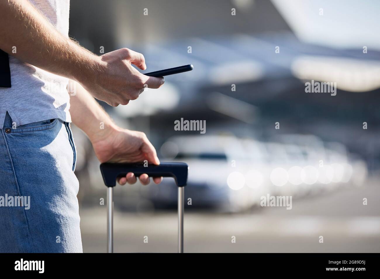 Man holding smartphone and using mobile app against a row of taxi cars. Themes modern technology, carsharing and travel. Stock Photo