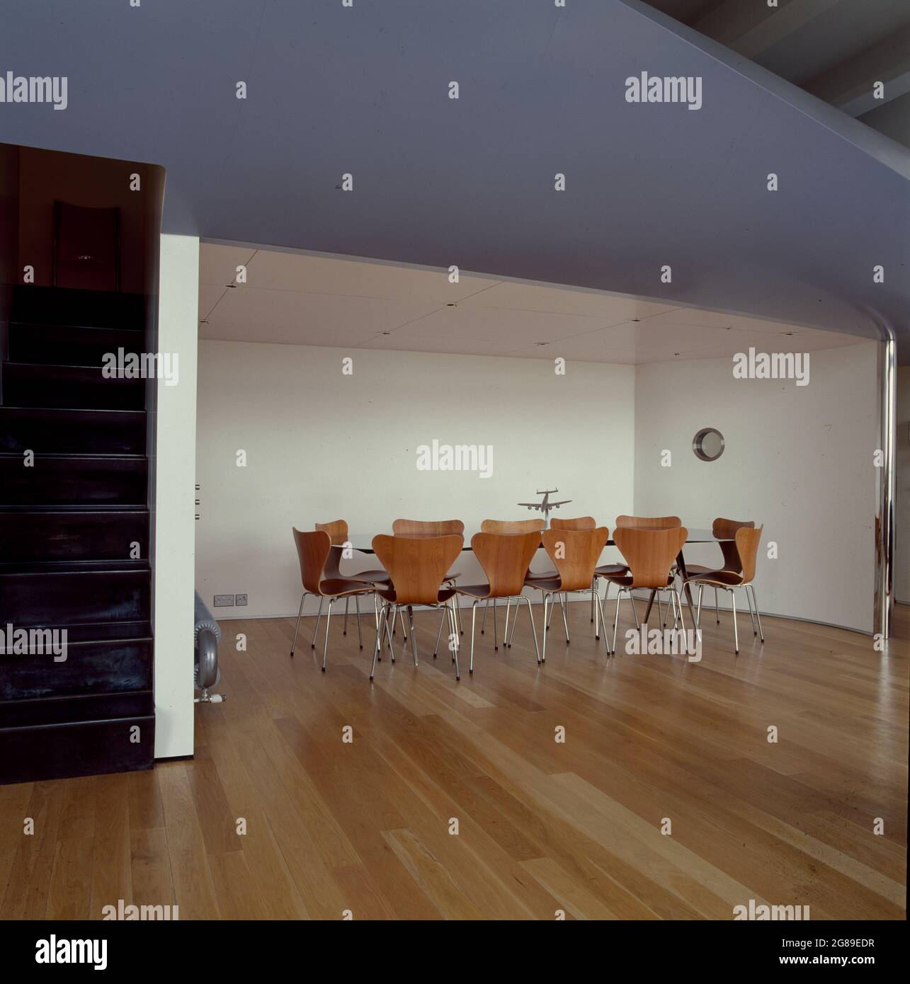 Large modern table with 12 chairs in empty architectural space. Stock Photo