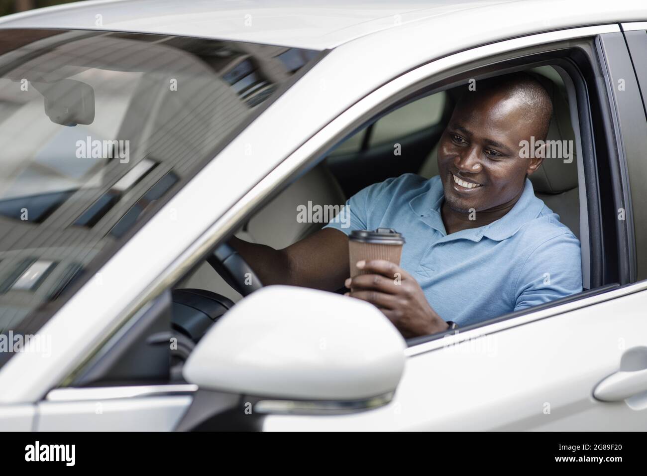 Relaxed black driver enjoying coffee break inside car Stock Photo