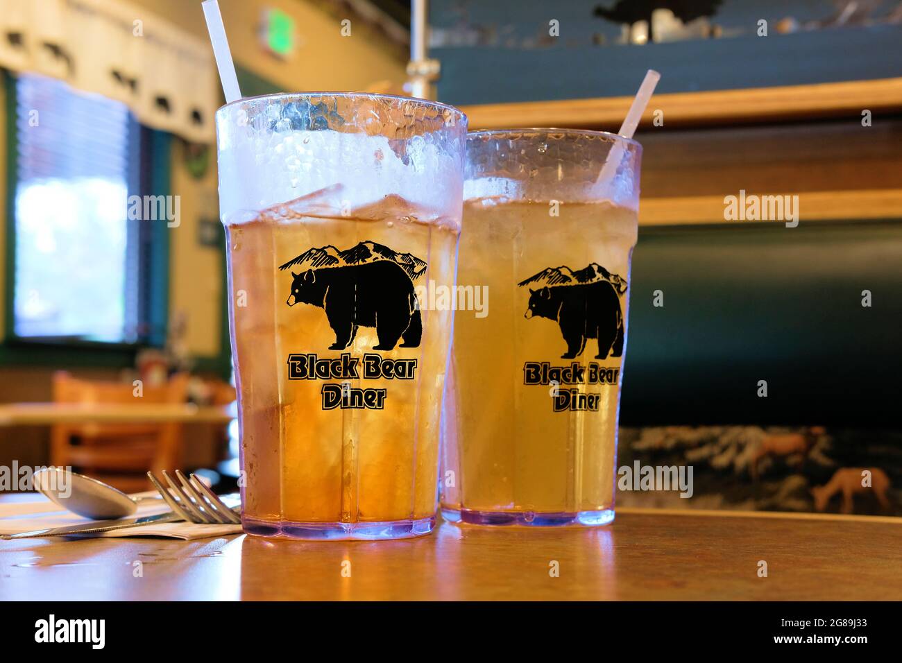 Two plastic iced tea glasses with Black Bear Diner logo on a table; a