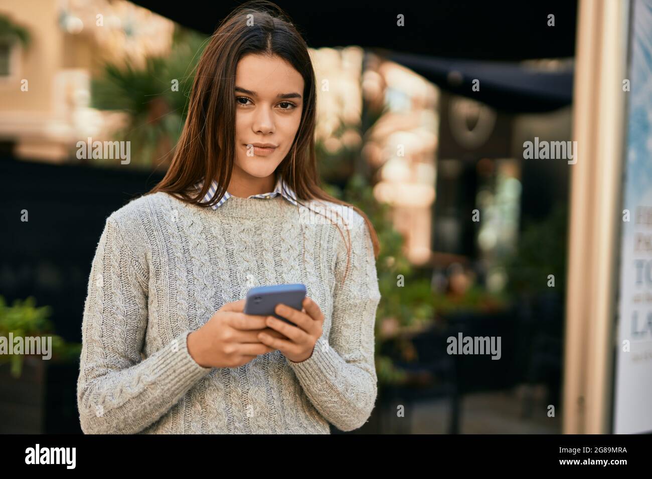 Young hispanic girl smiling happy using smartphone at the city Stock ...