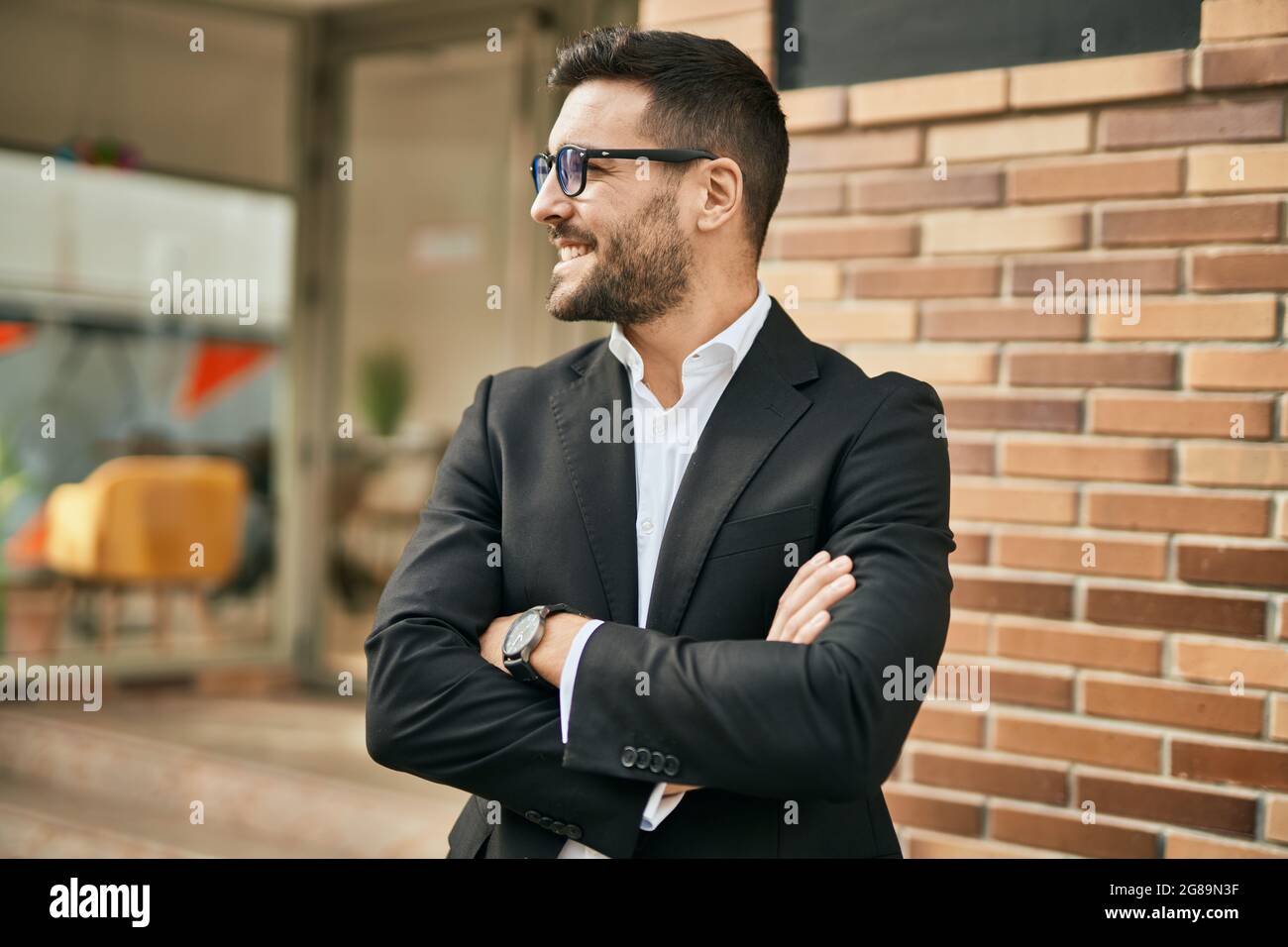 Young hispanic businessman with arms crossed smiling happy at the city ...