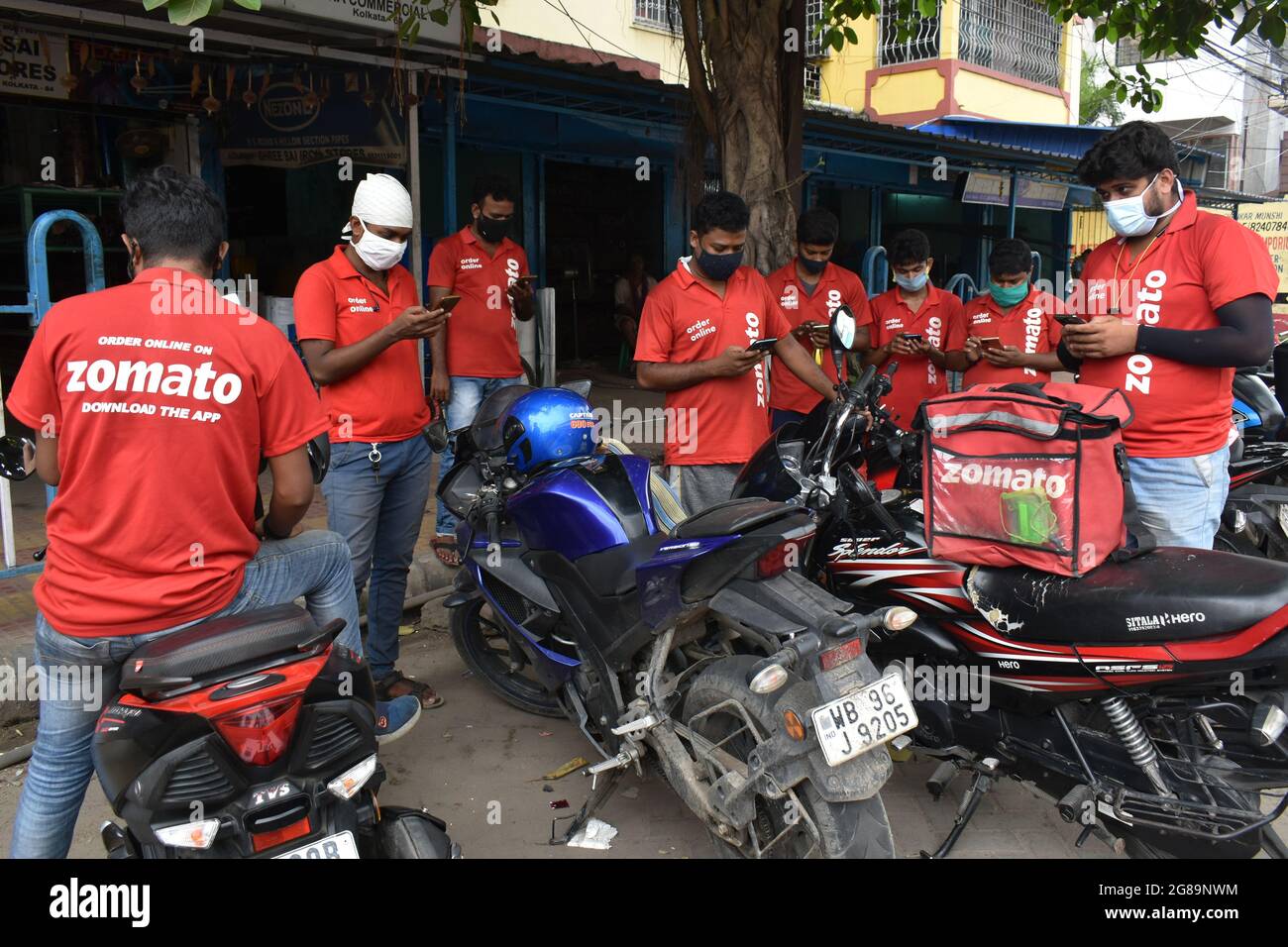 Kolkata, India. 17th July, 2021. Delivery workers of Zomato, an Indian food-delivery start-up, wearing face masks check their phones as they wait to collect orders outside a restaurant in Kolkata. (Photo by Sudipta Das/Pacific Press/Sipa USA) Credit: Sipa USA/Alamy Live News Stock Photo