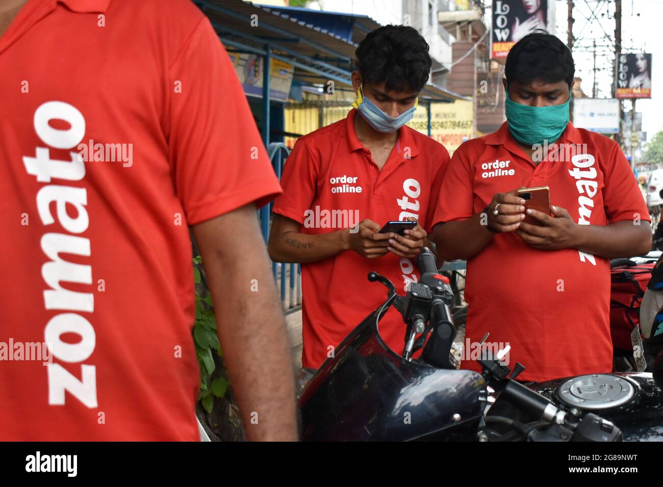 Kolkata, India. 17th July, 2021. Delivery workers of Zomato, an Indian food-delivery start-up, wearing face masks check their phones as they wait to collect orders outside a restaurant in Kolkata (Photo by Sudipta Das/Pacific Press/Sipa USA) Credit: Sipa USA/Alamy Live News Stock Photo