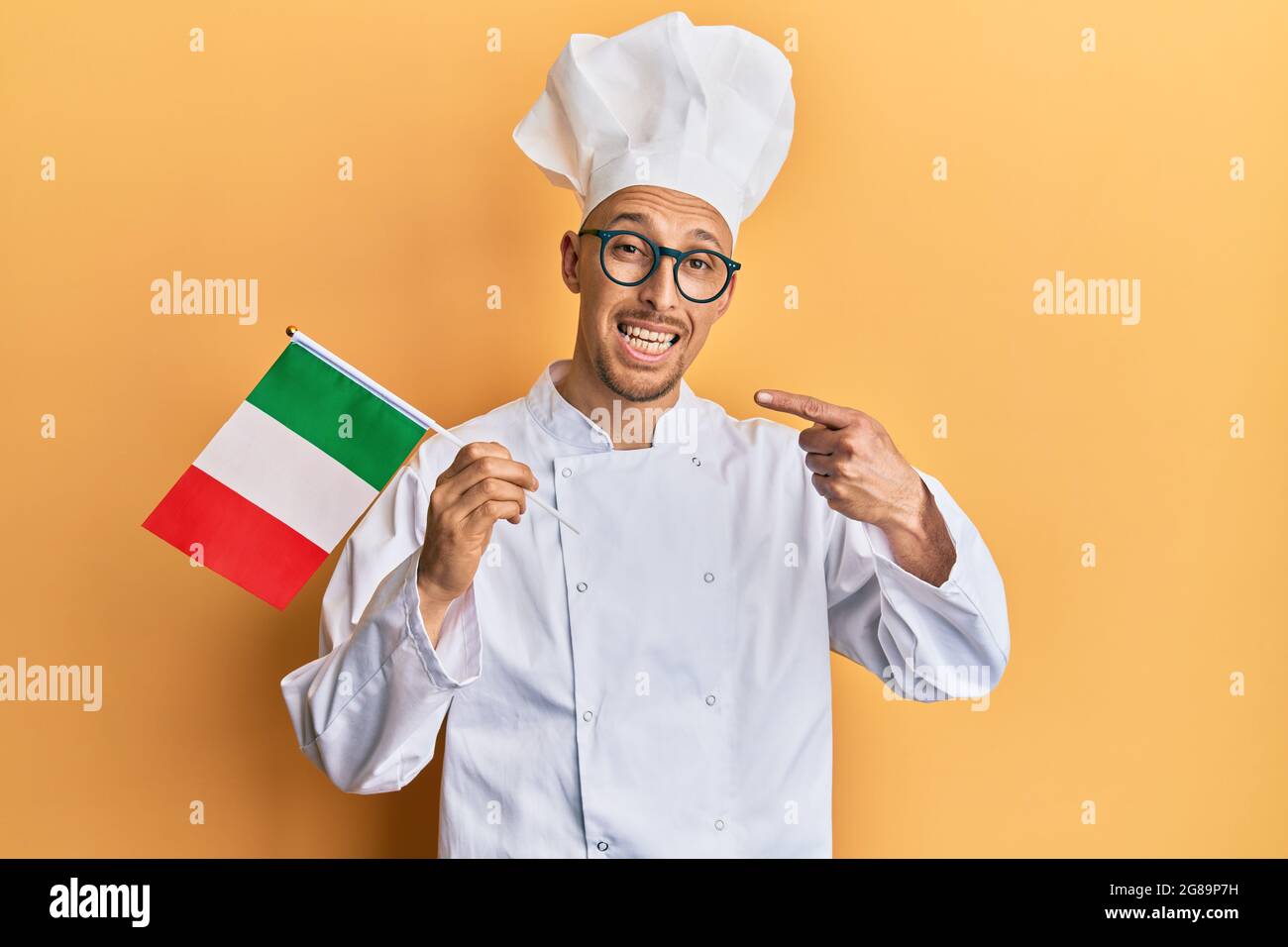 Bald man with beard wearing professional cook uniform holding italian ...