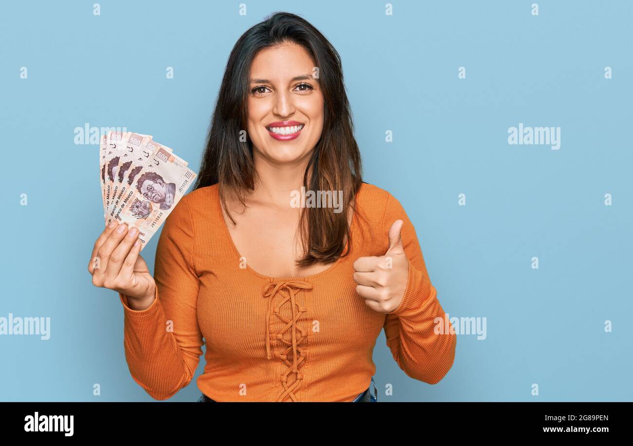 Beautiful hispanic woman holding mexican pesos smiling happy and ...