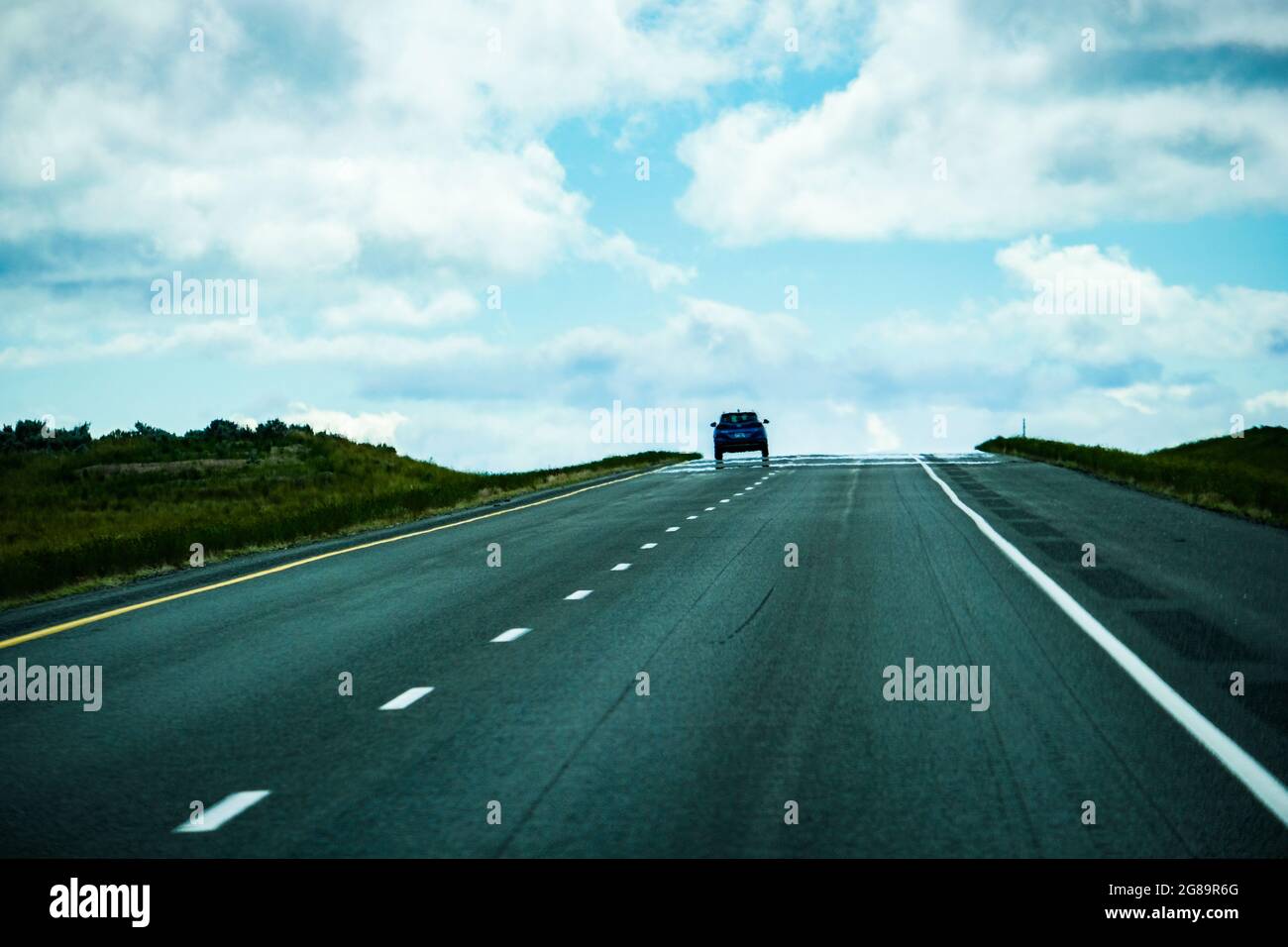 A car is silhouetted as it tops a hill on an Interstate in USA. Stock Photo