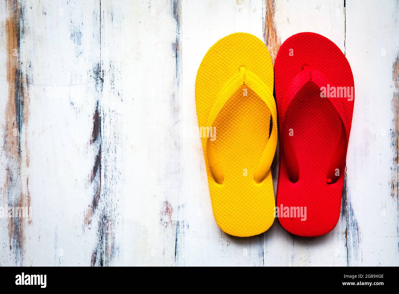 pair of and yellow rubber slippers popular use on a sand beach and tropical tourist destinations on wood background with sunlight and c Stock Photo - Alamy