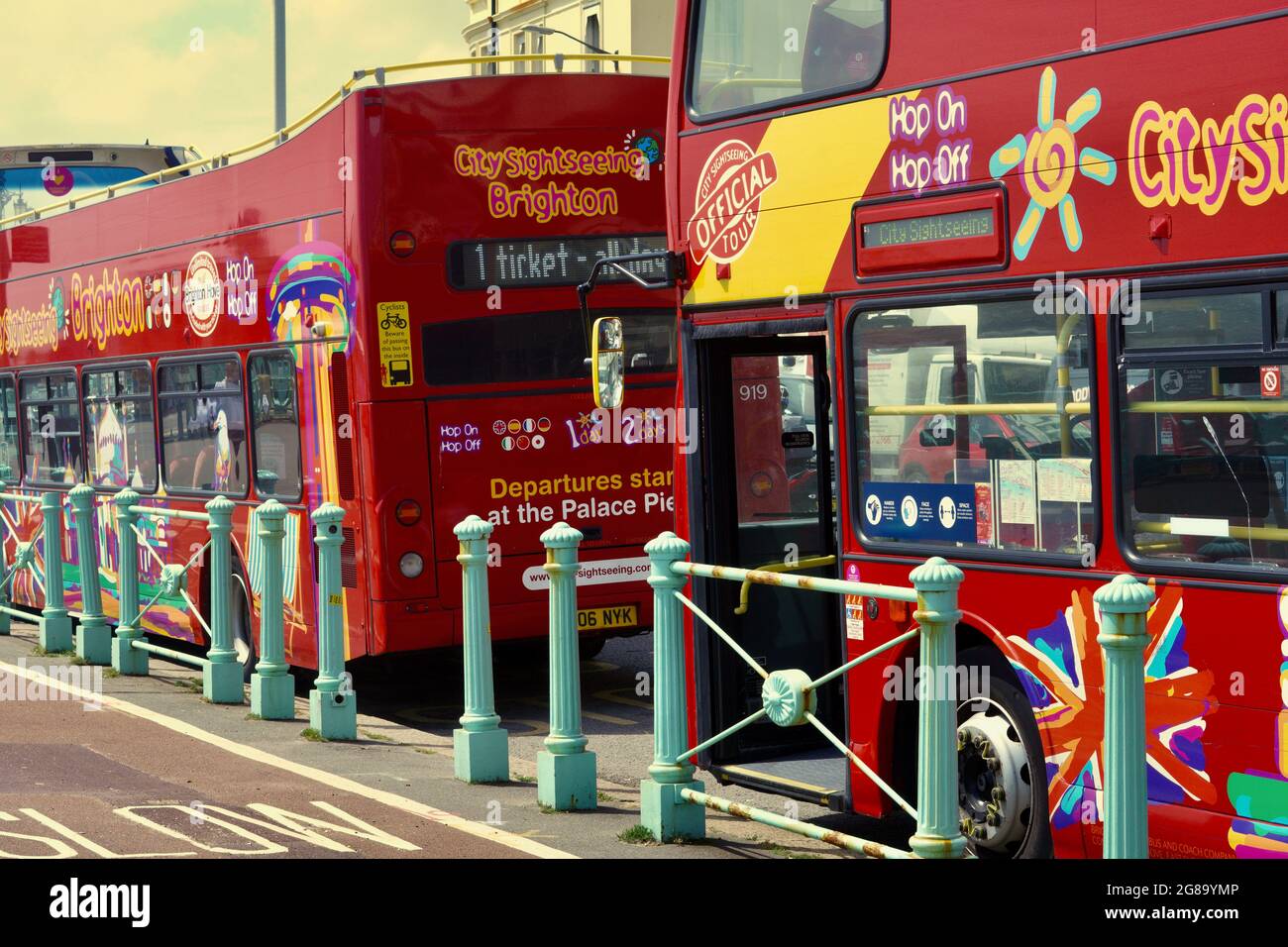 Brightly coloured double decker tour buses wait at the bus stops to ...