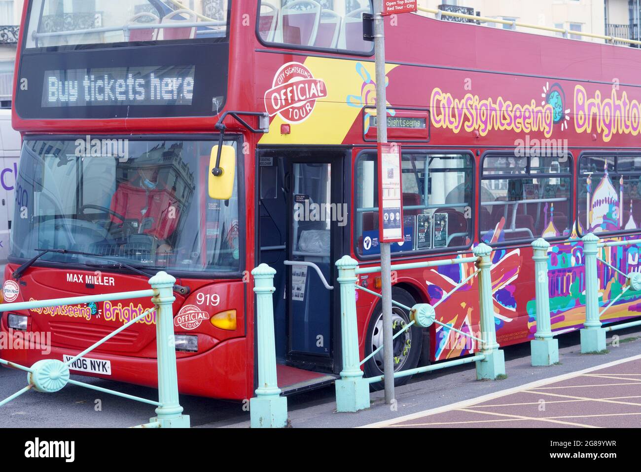 Brightly coloured double decker tour buses wait at the bus stops to