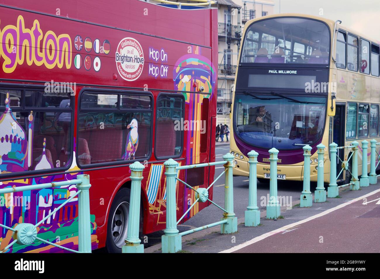 Brightly coloured double decker tour buses wait at the bus stops to collect passengers for their trips along the coast from Brighton to Eastbourne Stock Photo