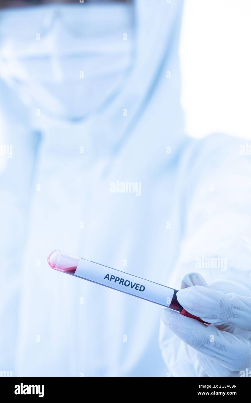Hand of researcher in sterilize protective dress holding approved test