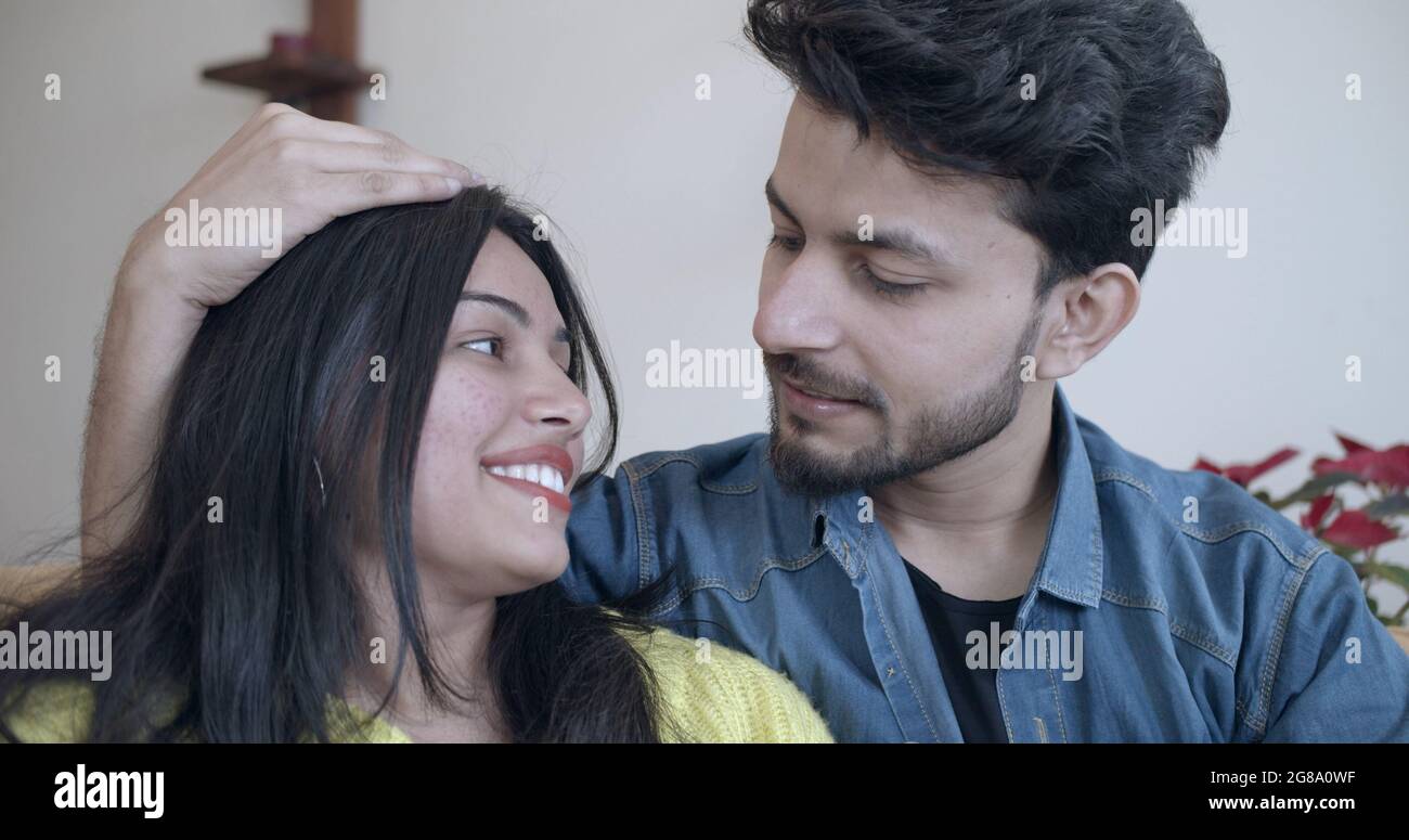 A young Indian couple touching each other while happily talking and ...