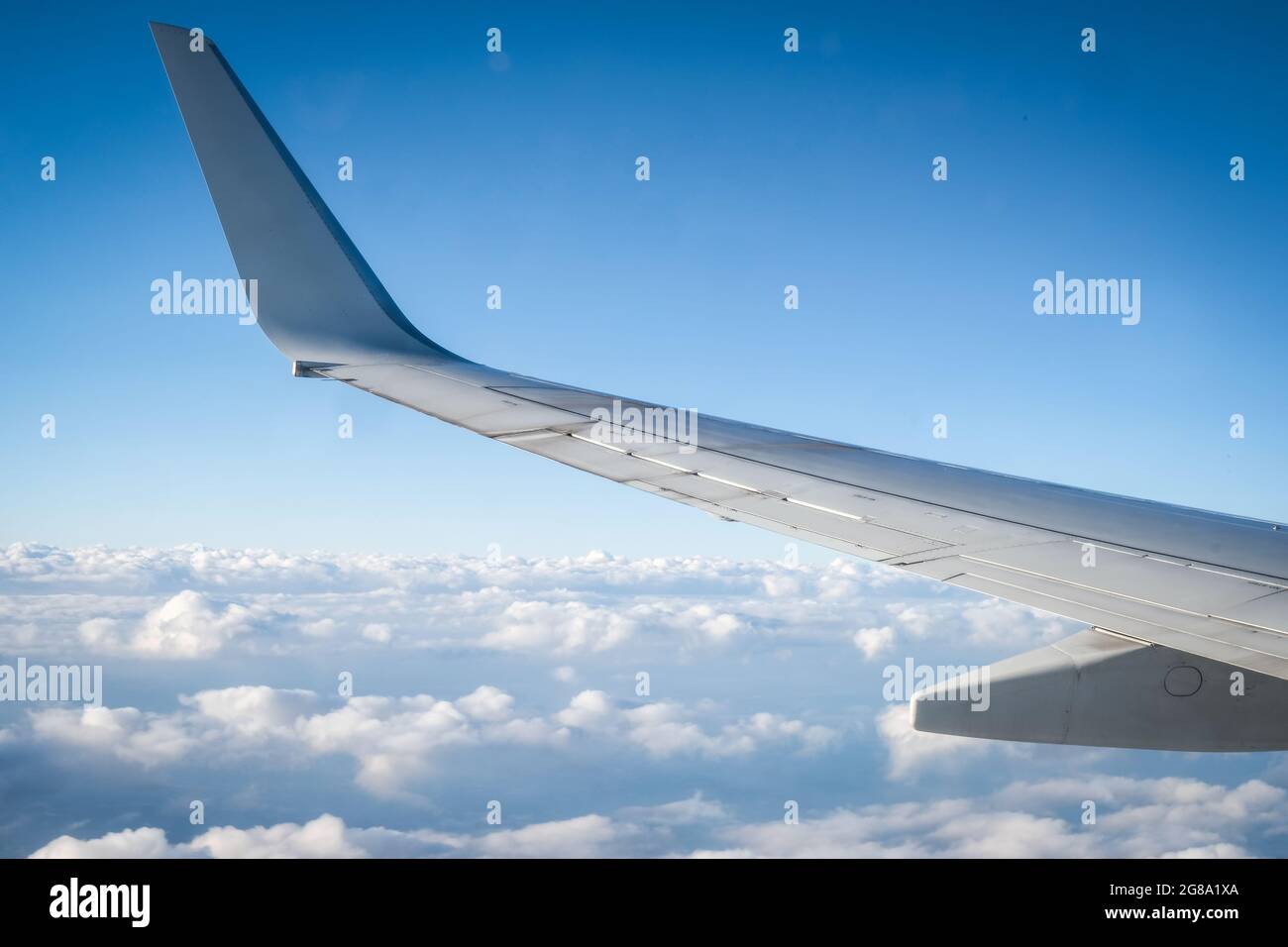 Flying above the clouds: airplane wing and cumulous clouds Stock Photo
