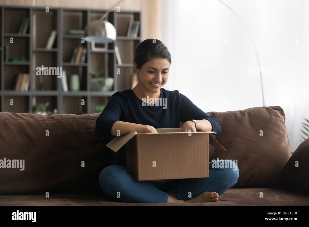Excited Indian woman unpack box with internet order Stock Photo