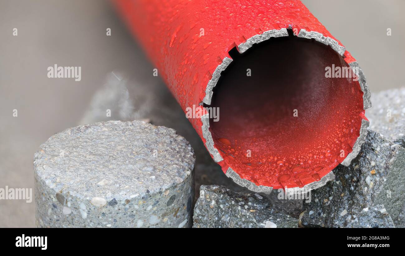 Red water cooled diamond core drill bit on round bored piece of gray concrete tile. Tool to wet drilling to masonry, stone and hard building materials. Stock Photo