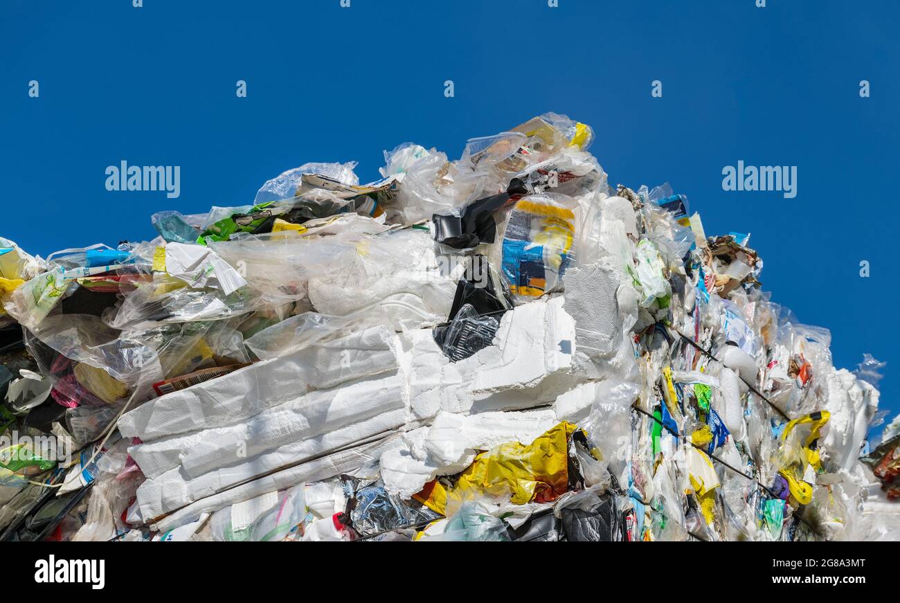 Detail of empty disposable plastic wrappings compressed in bale on blue sky background. Waste separation to recycle. Used packagings as bag, sack, box. Stock Photo