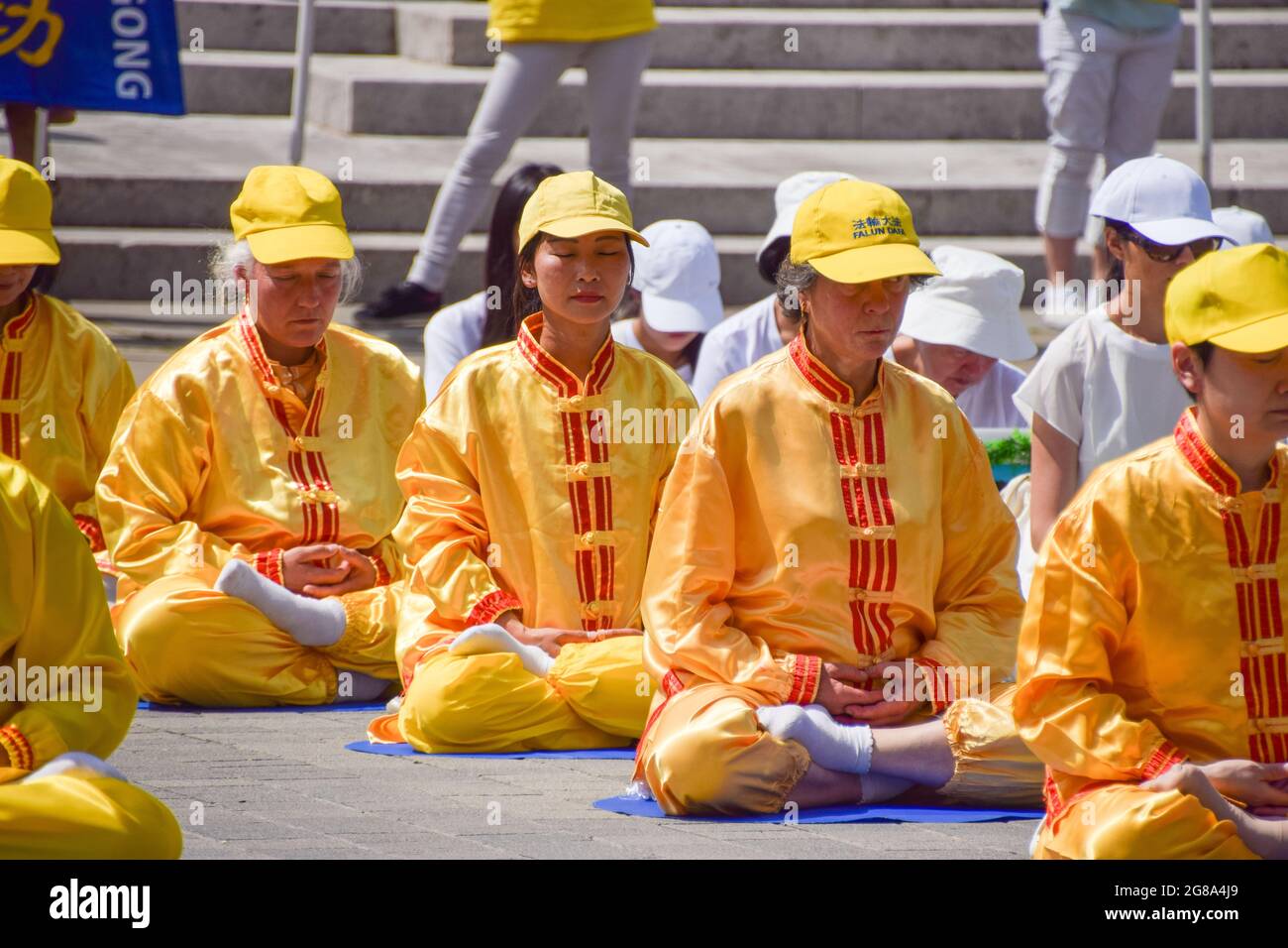 London, UK. 18th July, 2021. Falun Gong practitioners meditating during the protest.Practitioners and supporters gathered outside the Houses of Parliament to protest against the Chinese government's persecution, according to the protesters, of Falun Gong (also known as Falun Dafa) meditation practitioners, through abductions, imprisonment, torture, and organ harvesting. Credit: SOPA Images Limited/Alamy Live News Stock Photo