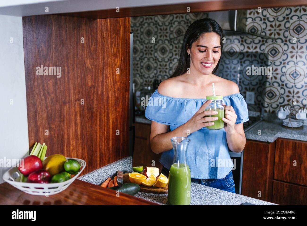 Latin Woman making green smoothie or Detox juice in kitchen at Home in healthy eating concept in Mexico Stock Photo