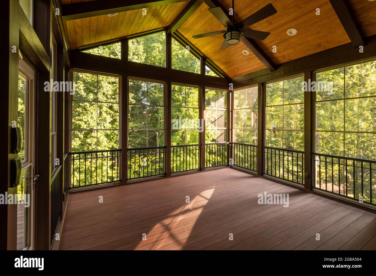 Modern screened porch with plastic windows and composite floor with summer woods in the background. Stock Photo