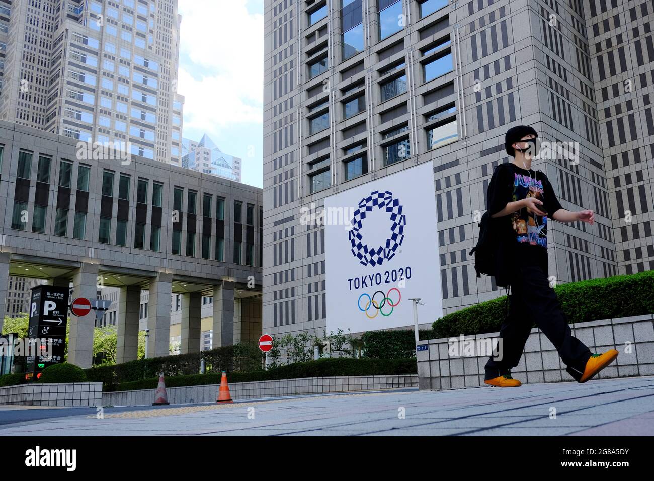 A man wearing a face mask as a preventive measure against the spread of coronavirus walks past a banner for the upcoming Tokyo 2020 Olympics in front of the Tokyo Metro Government building. (Photo by James Matsumoto / SOPA Images/Sipa USA) Stock Photo