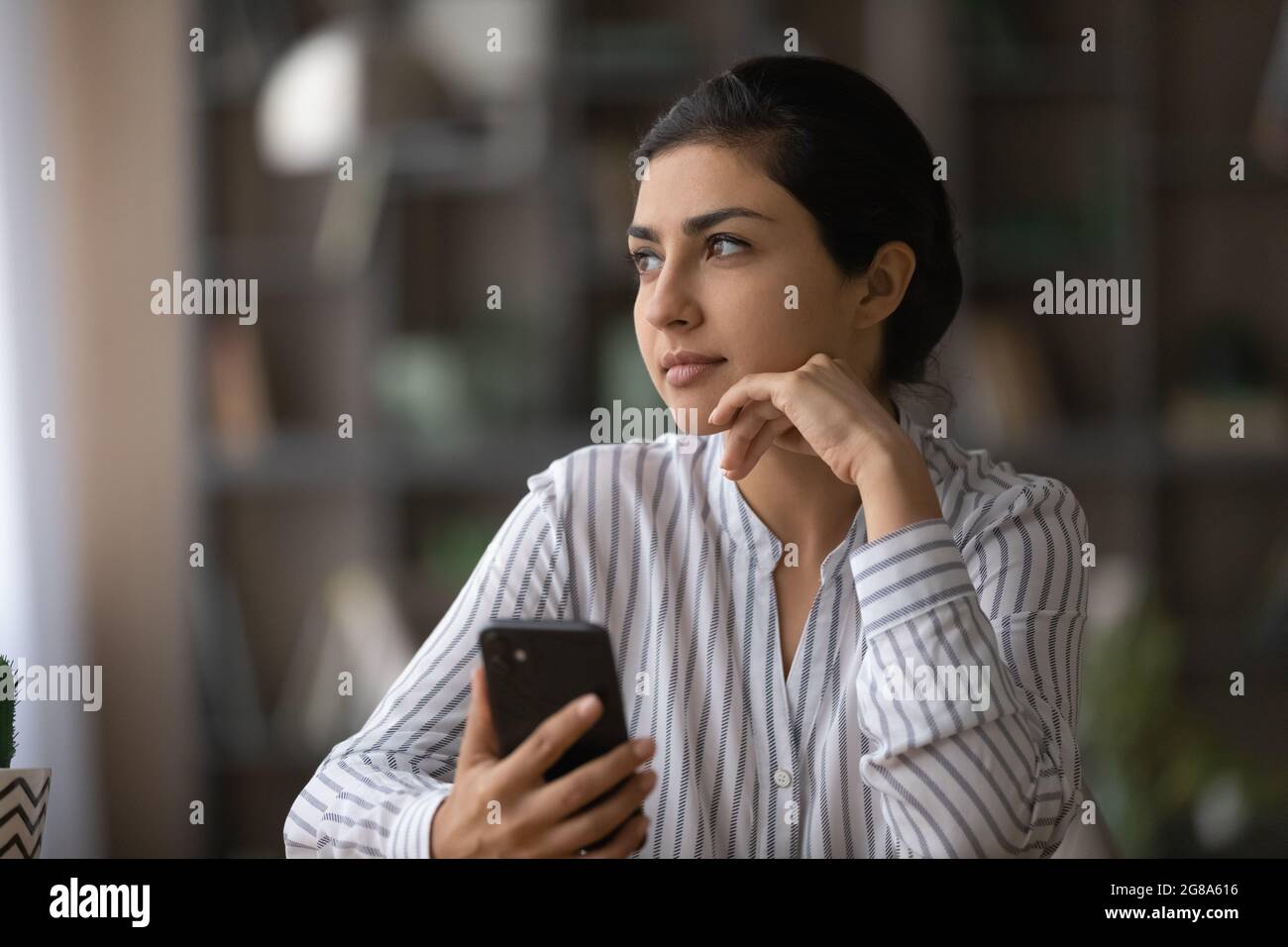 Pensive Indian woman use cellphone thinking planning Stock Photo - Alamy