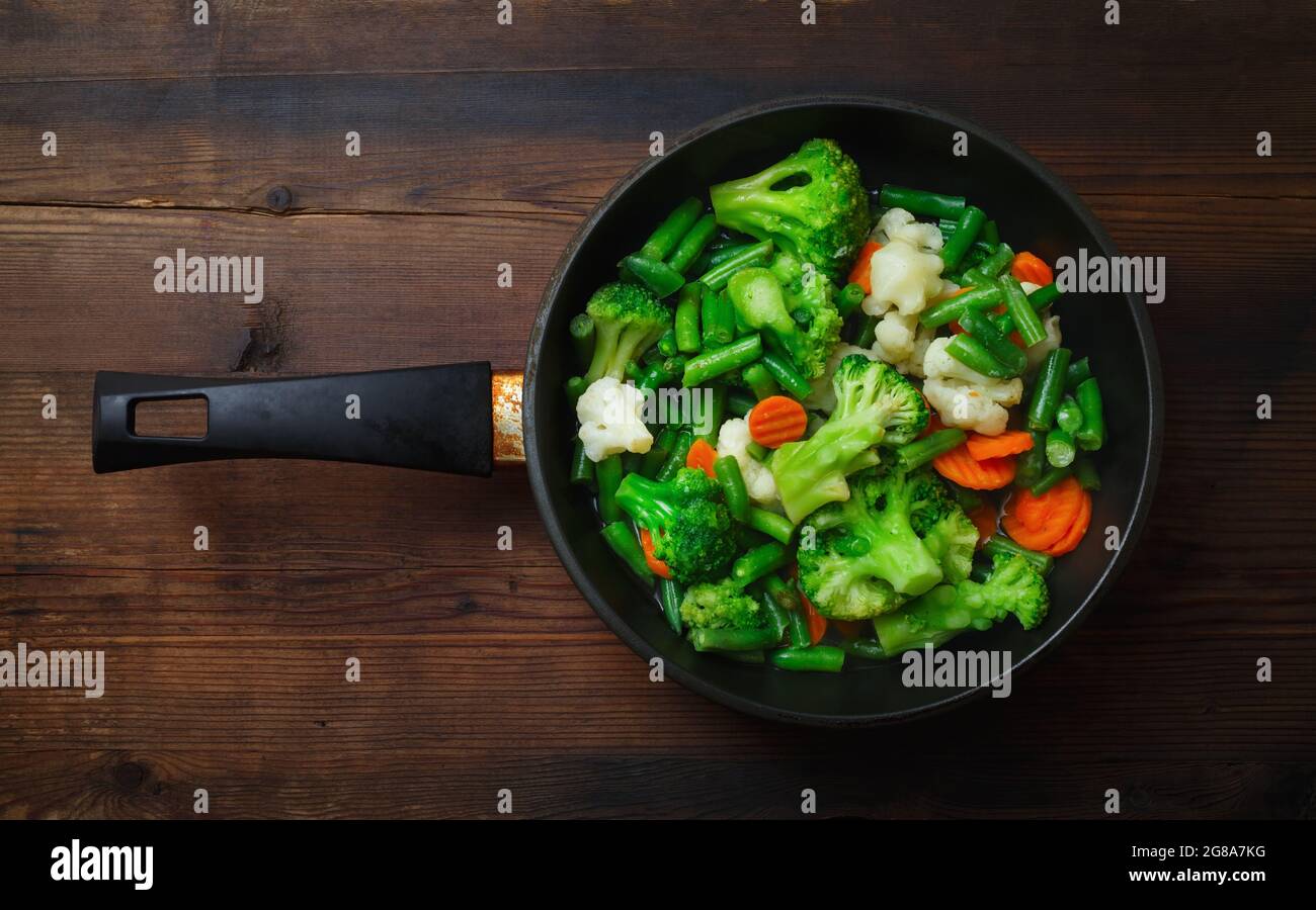 Fried vegetables in pan on wood table background. Flat lay. Stock Photo