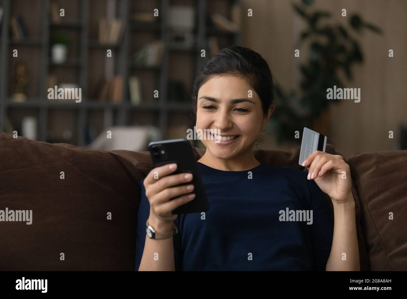 Smiling Indian female buyer shopping online on smartphone Stock Photo