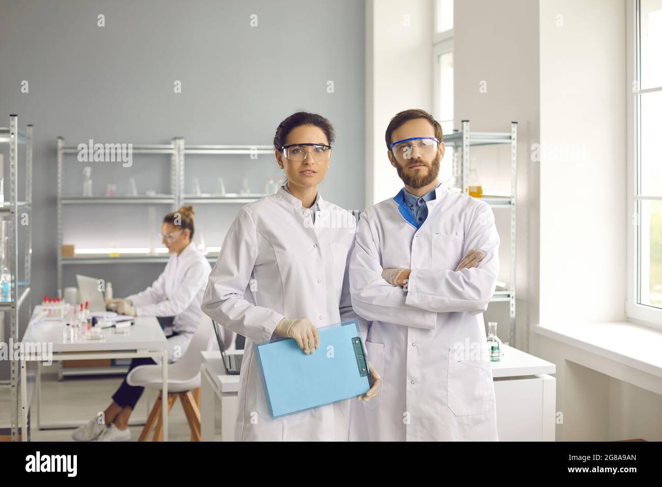 Portrait of scientists in lab coats and goggles standing in modern