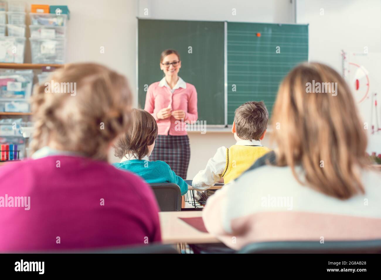 Teacher in school class with pupils sitting and listening Stock Photo