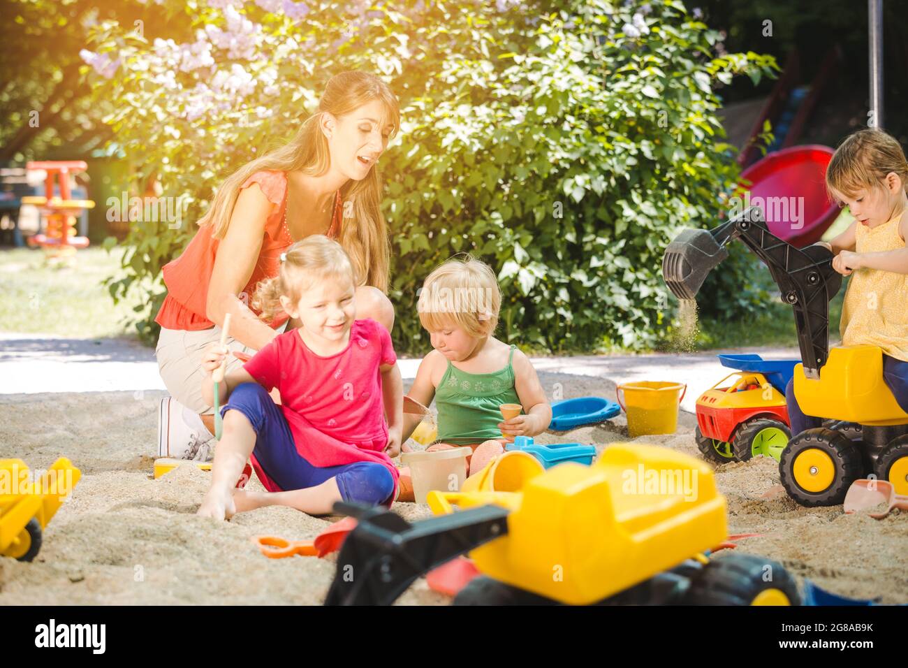 Children and play school teacher enjoying some time in sand box Stock Photo