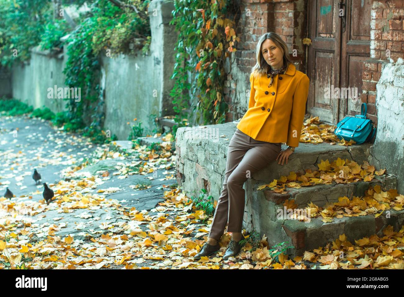 An woman posing in an autumn street with foliage Stock Photo - Alamy