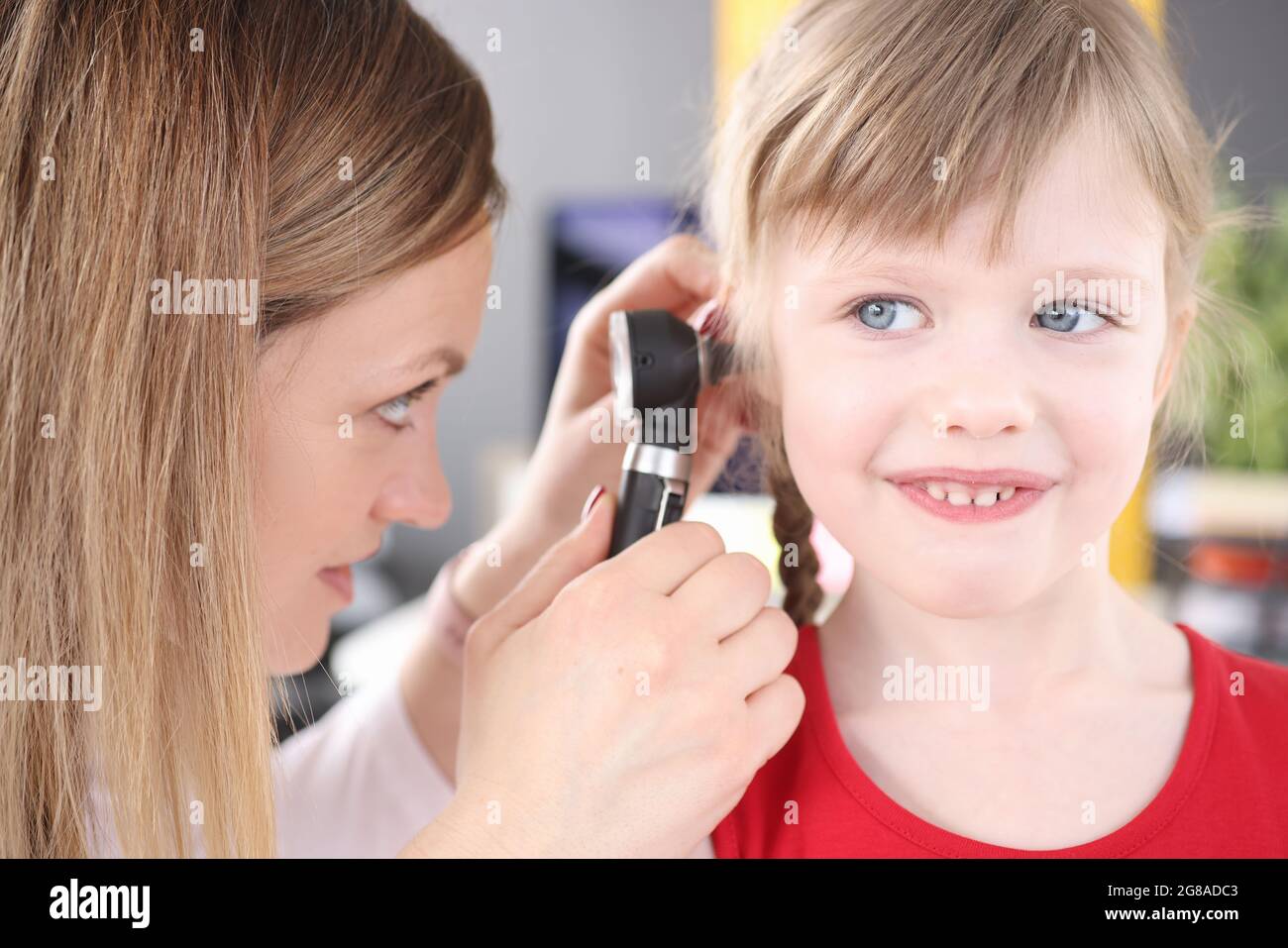 Otorhinolaryngologist conducts medical examination of little girl ear
