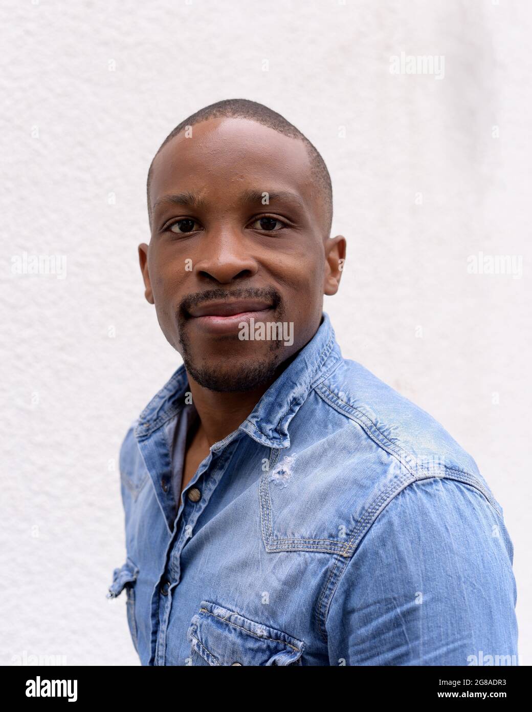 Young man in casual blue denim shirt with a plane background. Stock Photo