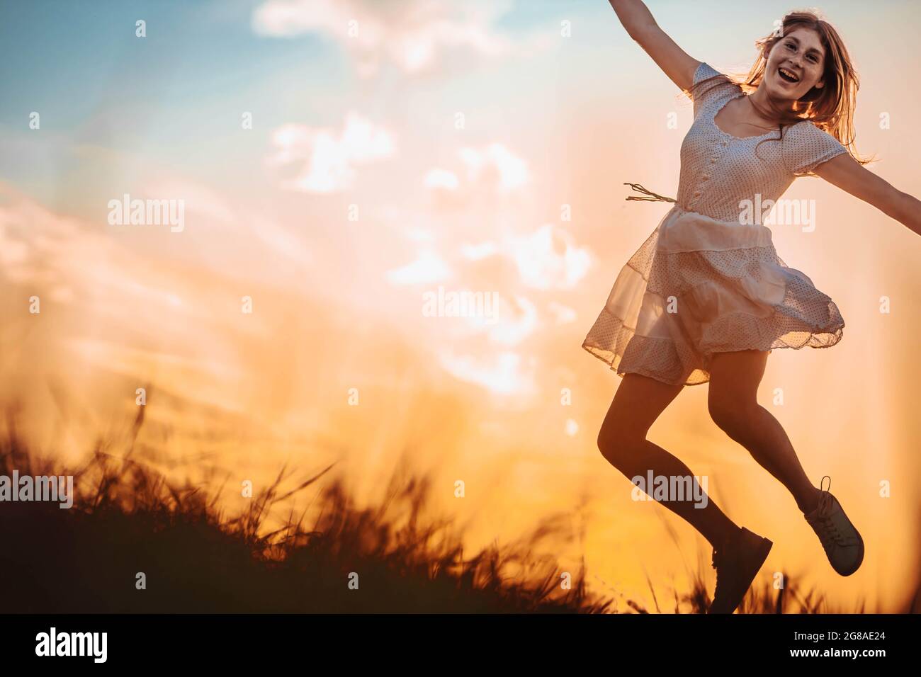 Outdoors photo of young, teen, ginger girl jumping, looking very happy and excited. Copy space Stock Photo