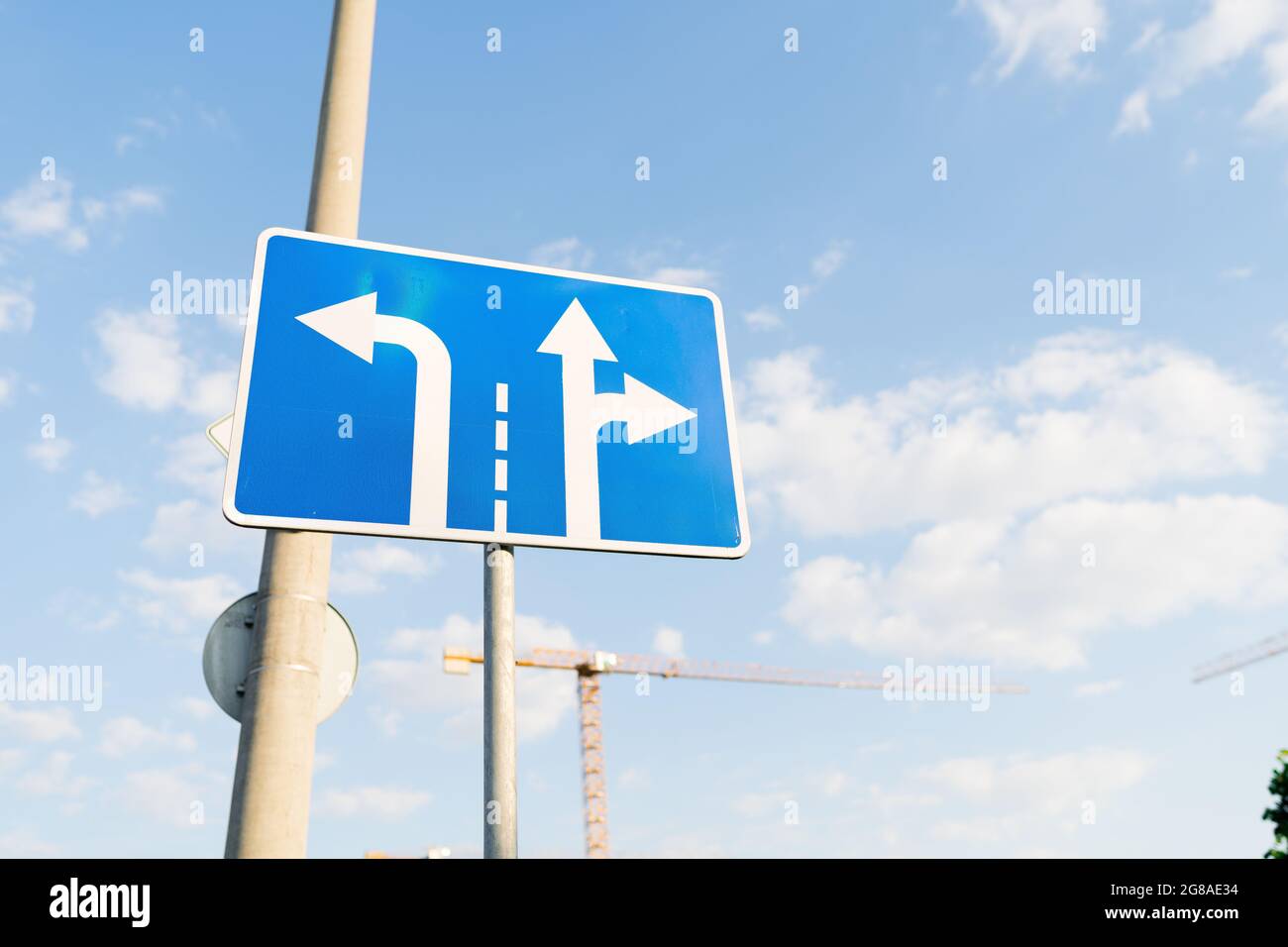 Blue traffic sign indicating rules of turn on thetraffic lanes with blue sky on the background. Stock Photo