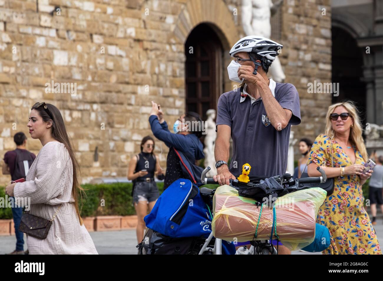 Man tourist with a bike next to Uffizi museum and David sculpture, wearing face masks during covid 19 quarantine in Italy. Slow reopening Stock Photo