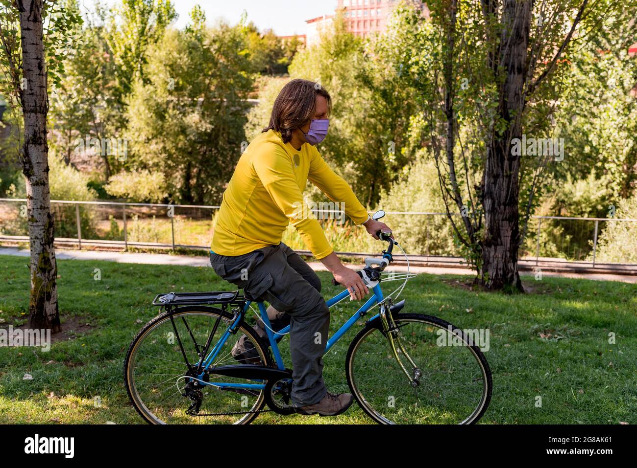 Man wearing face mask in the park riding bike Stock Photo - Alamy