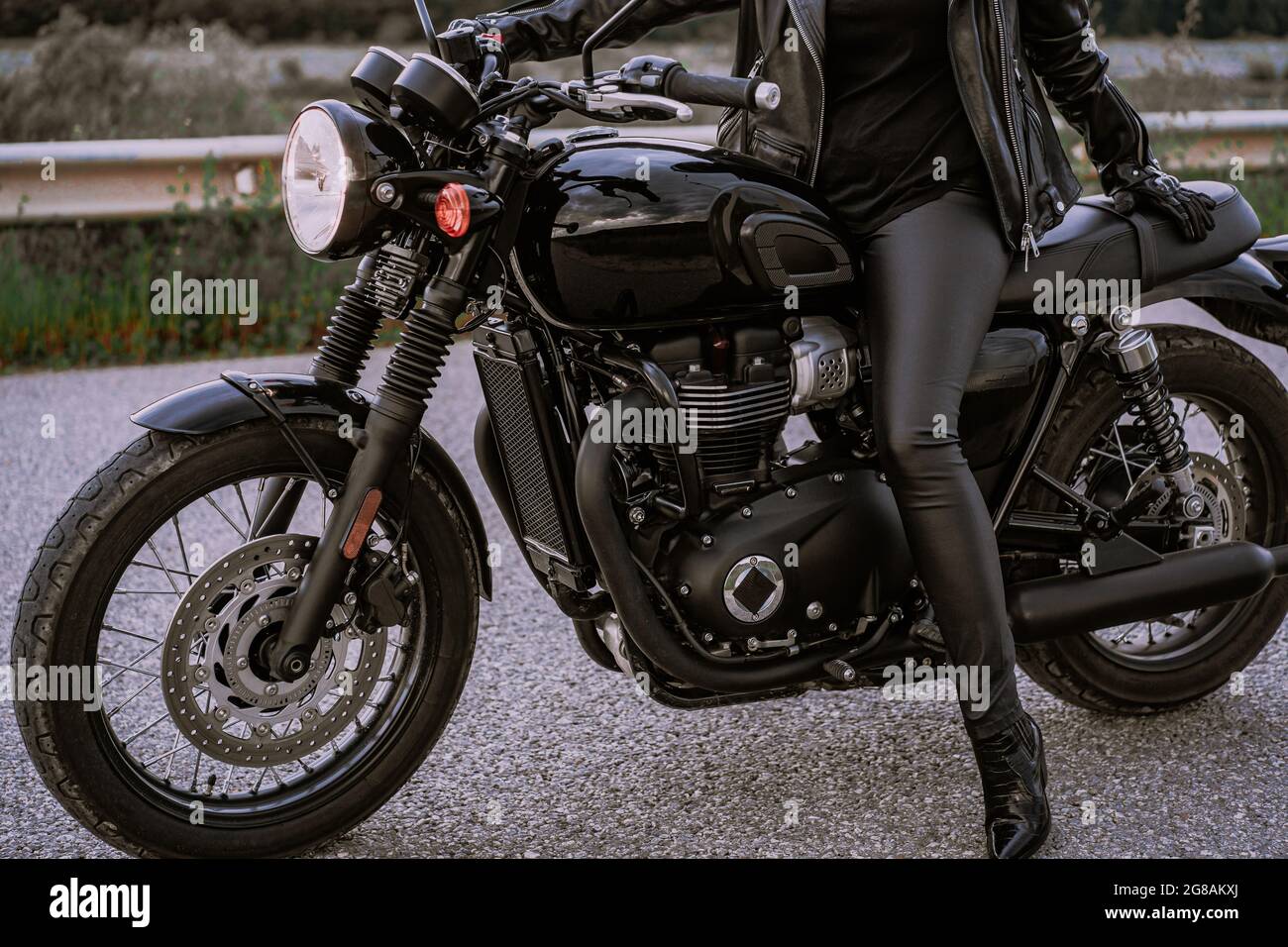 Legs of stylish motorcyclist woman sitting on classic bike. Black retro-styled  motorcycle. Details of vintage design of brand-new motorbike Stock Photo -  Alamy