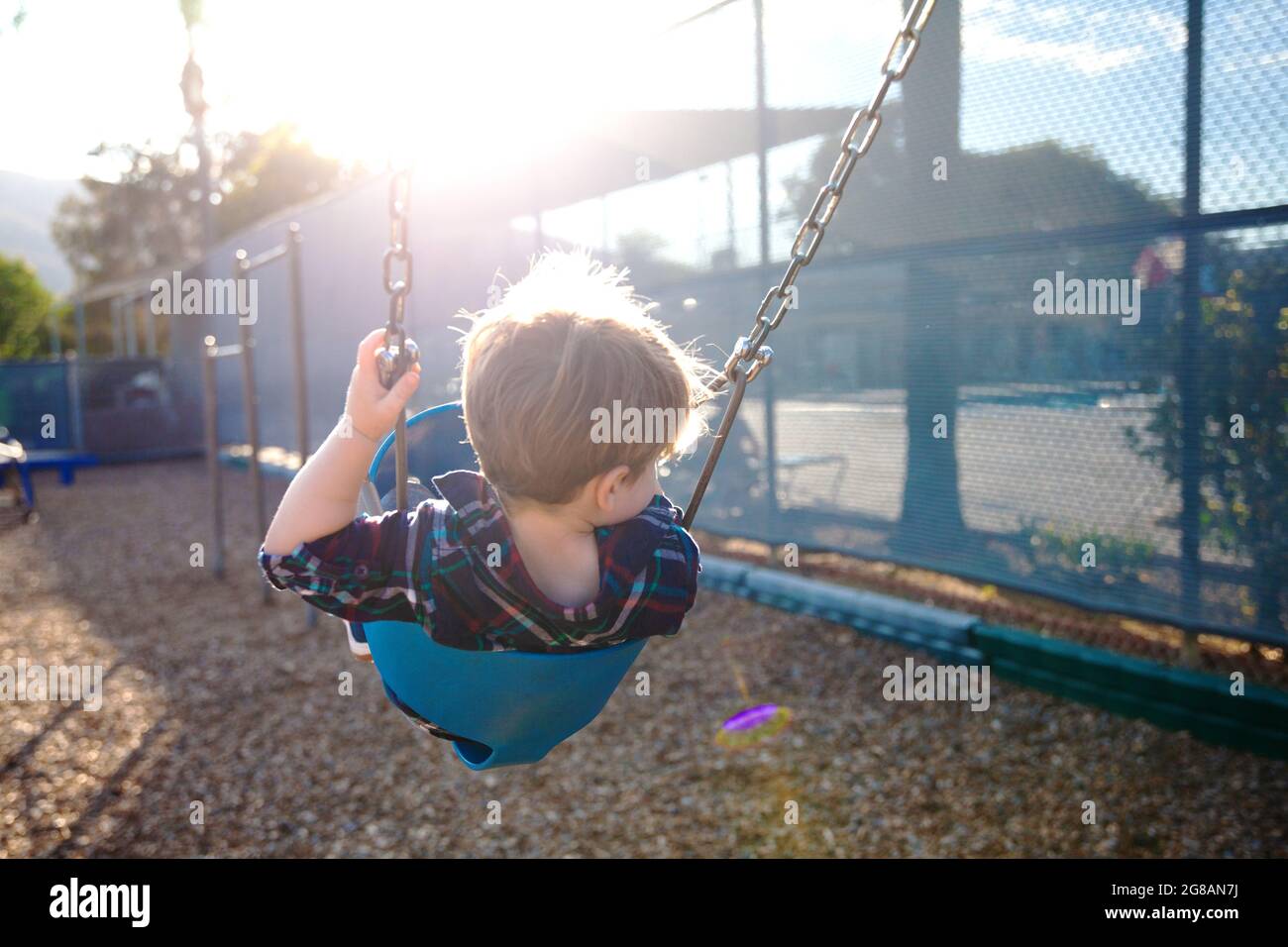 Modern colorful kids playground - swings, slides, steps and ladders. Outdoor plastic playing area for children.  Little boy on swing and slide. Stock Photo