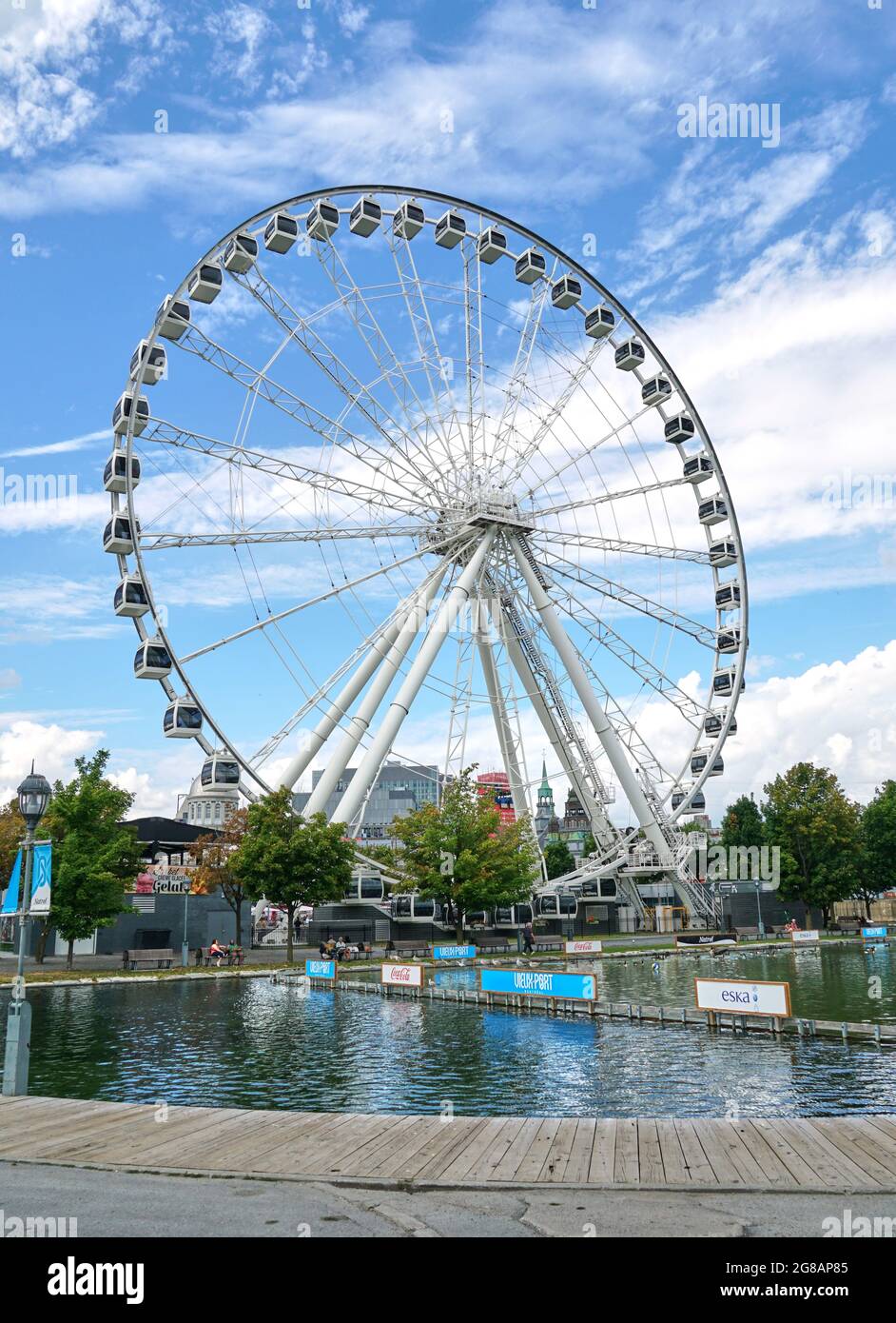 Canada, Montreal - July 11, 2021: Scenic view of ferris wheel La Grande Roue de Montreal in Old Port of Montreal over blue skies and clouds. The Old P Stock Photo