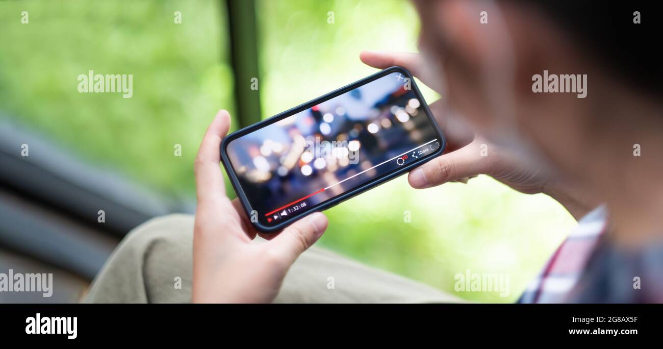 Cropped shot of female hand holding mobile phone playing video stream online. Stock Photo