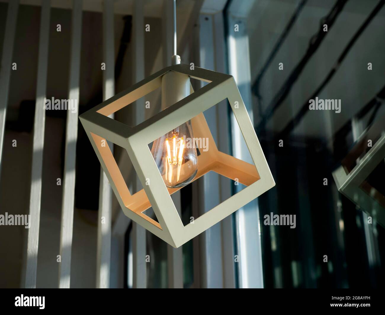 White cubic frame hanging with a light bulb. Modern ceiling lamp with