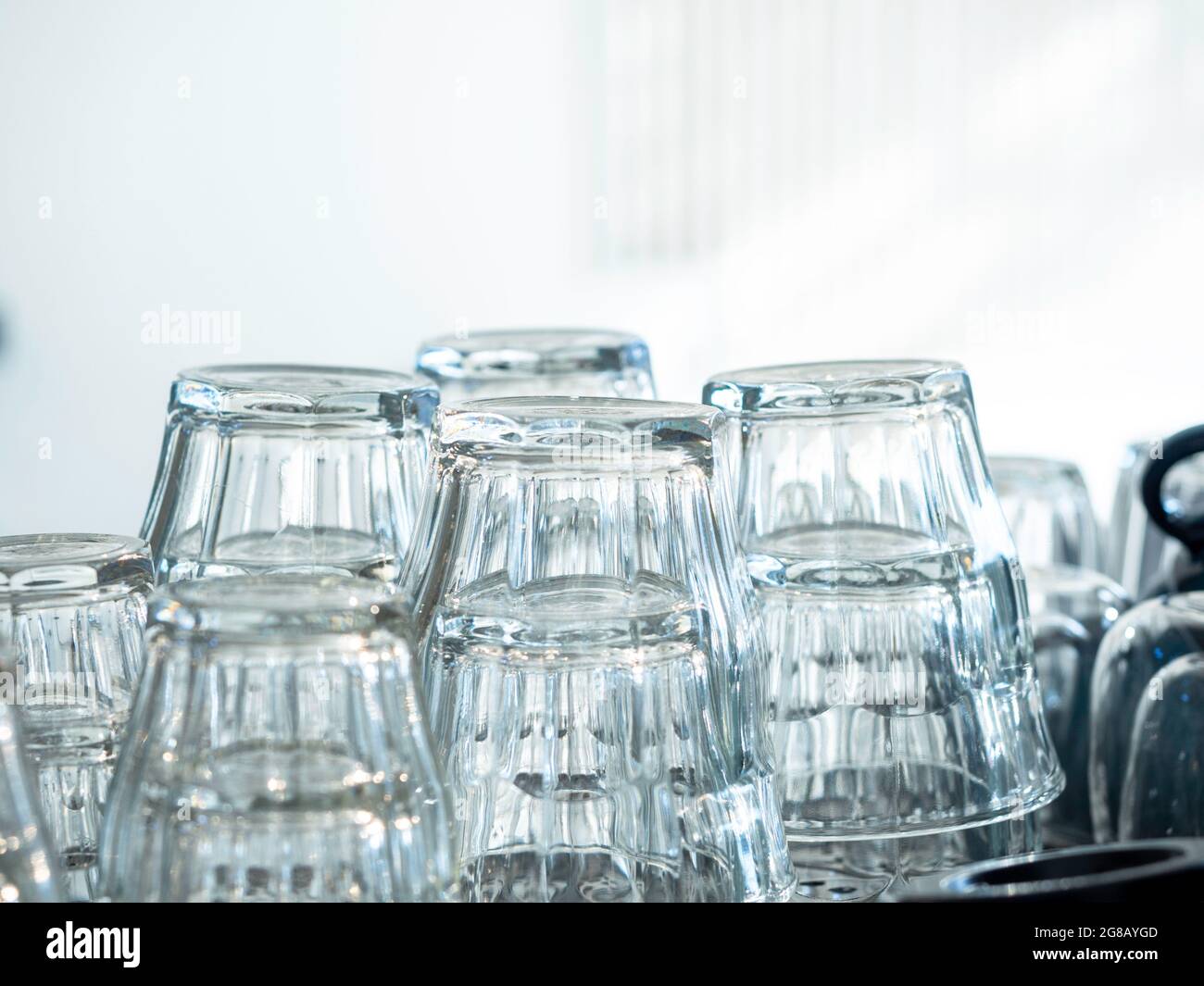 Close up upside down empty drinking water glasses. Stacks of clean and