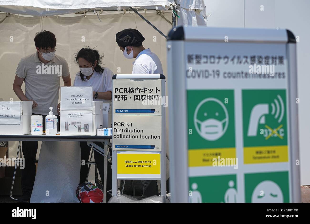 Tokio, Japan. 19th July, 2021. Employees stand at the collection point for the saliva samples from the Corona PCR test. The Olympic Games 2020 Tokyo will take place from 23.07.2021 to 08.08.2021. Credit: Michael Kappeler/dpa/Alamy Live News Stock Photo