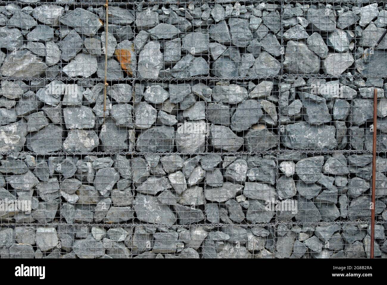 The texture of a fence made of many gray stones, reinforced with a metal mesh. Background. Stock Photo