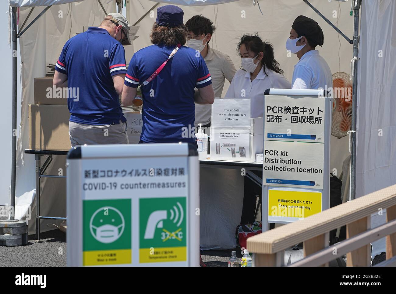 Tokio, Japan. 19th July, 2021. Two men give their saliva sample for the Corona PCR test at a collection point. The 2020 Tokyo Olympics will take place from 23.07.2021 to 08.08.2021. Credit: Michael Kappeler/dpa/Alamy Live News Stock Photo
